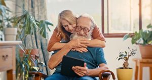 happy-senior-couple-and-with-tablet-gets-news-bonding-and-on-social-media-while-at-home-in-living-room-married-man-and-woman-being-excited-online-scroll-and-hug-for-notification-and-video-call
